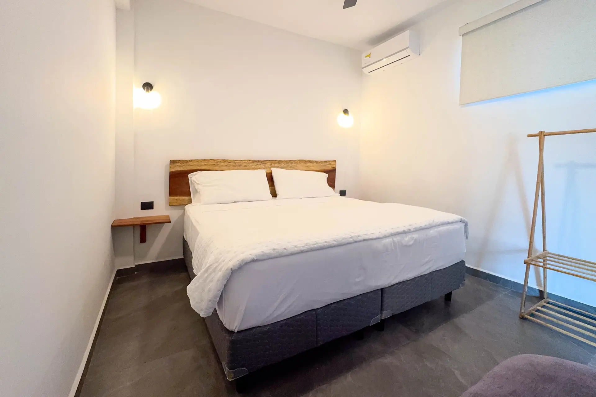 Recámara con cama king, cabecera de madera, aire acondicionado y un burro para maletas
